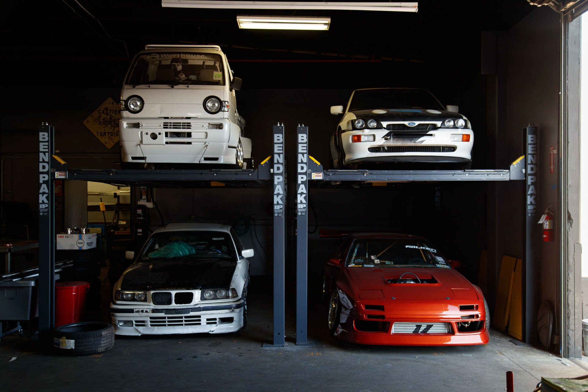 Workshop bays at night with cars stacked on four-post lifts