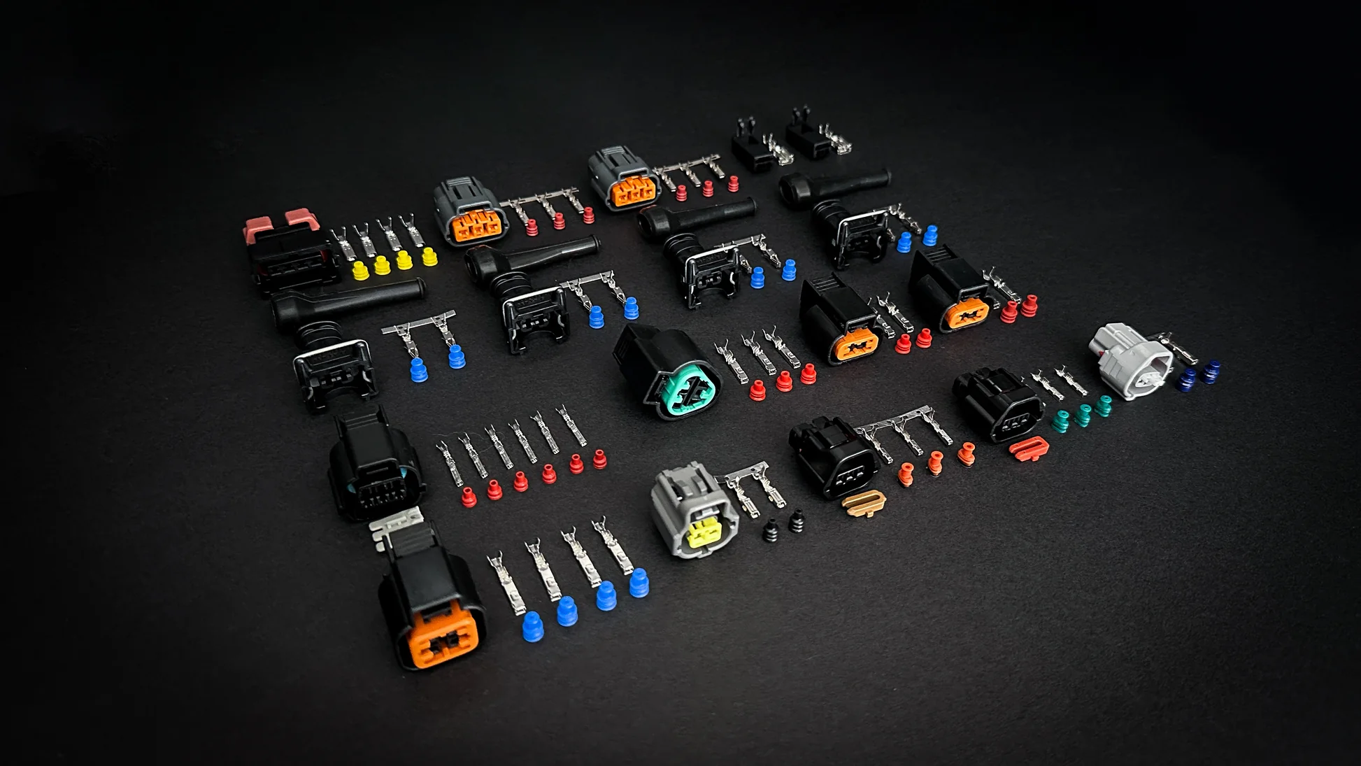 Automotive loom connectors, terminals and seals laid out on a dark surface