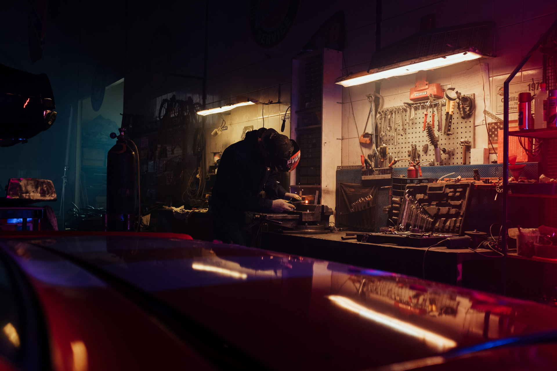 Mechanic working at a bench under a single lamp in a dark workshop